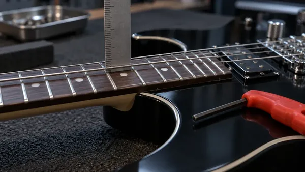Regla metálica apoyada sobre el traste doce de una guitarra eléctrica